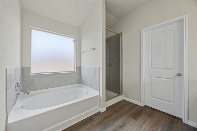 bathroom with vaulted ceiling, hardwood / wood-style flooring, and plus walk in shower