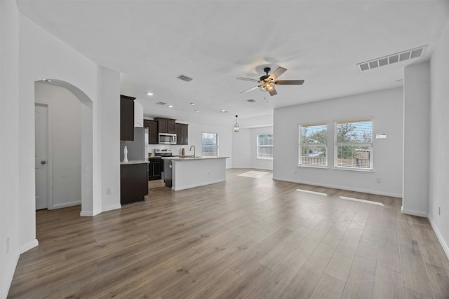 unfurnished living room with ceiling fan, sink, and hardwood / wood-style floors