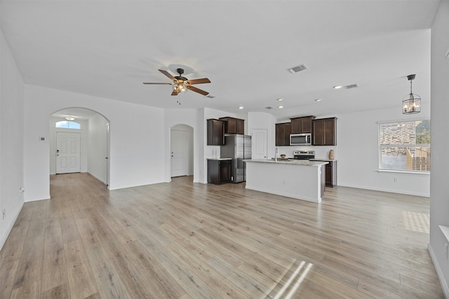 unfurnished living room featuring light wood-type flooring, ceiling fan with notable chandelier, and sink