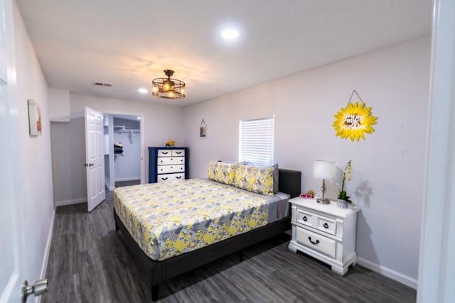 bedroom with a closet, dark hardwood / wood-style flooring, and a walk in closet