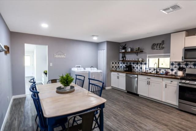 kitchen with tasteful backsplash, white cabinetry, appliances with stainless steel finishes, dark wood-type flooring, and separate washer and dryer