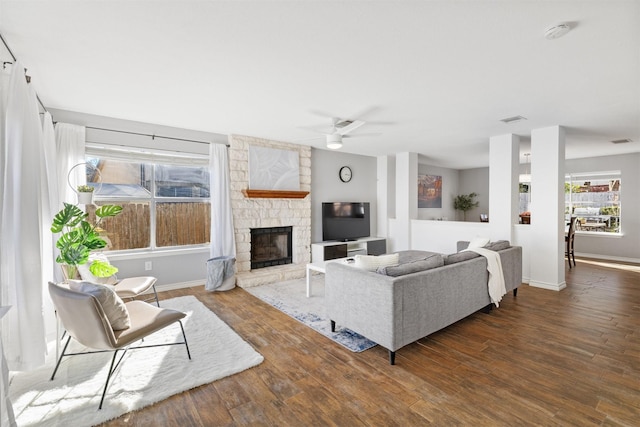 living room with dark wood-type flooring, ceiling fan, and a fireplace