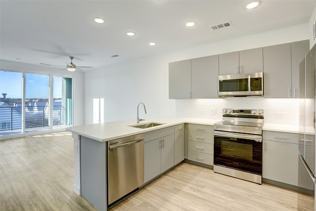 kitchen with sink, ceiling fan, kitchen peninsula, gray cabinetry, and appliances with stainless steel finishes