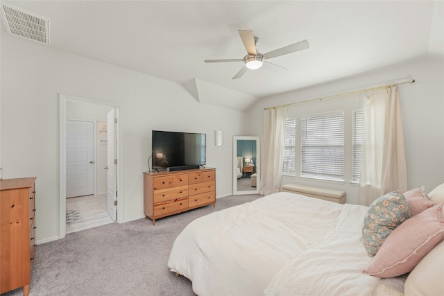 carpeted bedroom with ceiling fan, ensuite bathroom, and vaulted ceiling