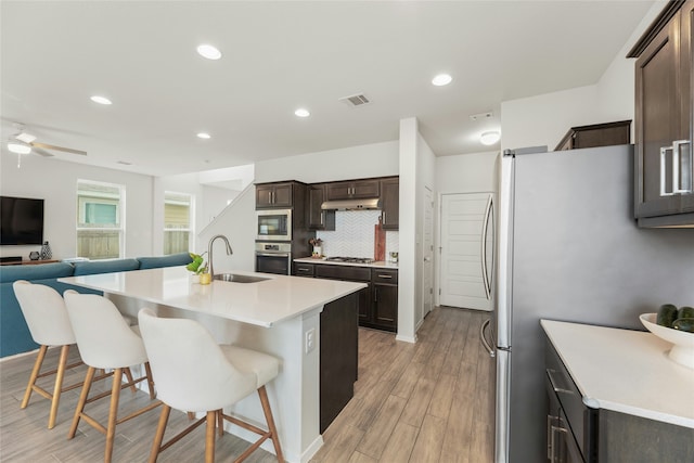 kitchen with an island with sink, stainless steel appliances, tasteful backsplash, a kitchen bar, and sink