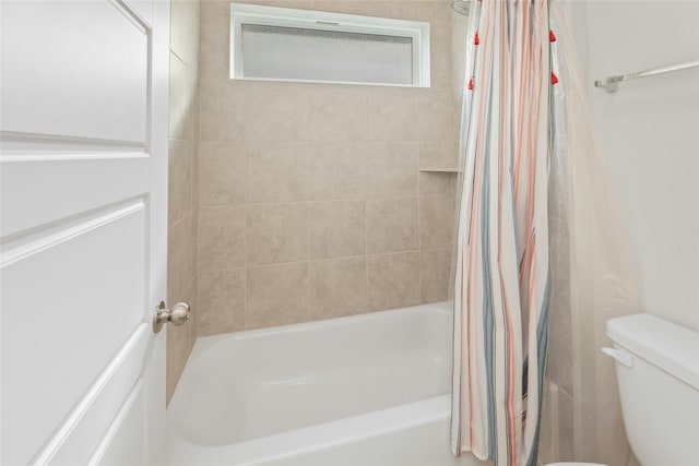 bathroom featuring toilet and shower / bath combination with curtain