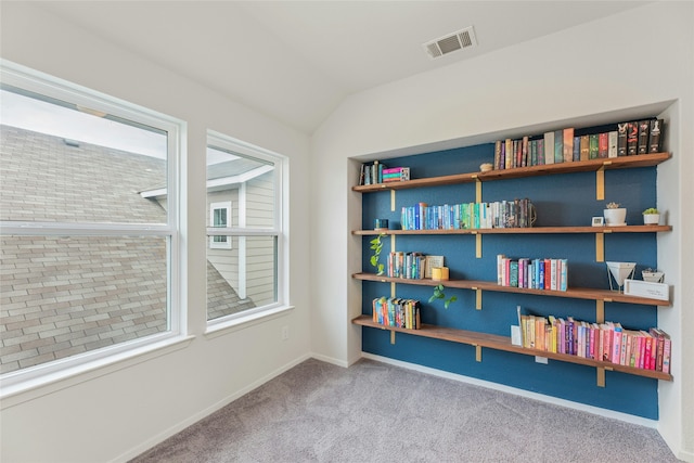 sitting room with lofted ceiling, plenty of natural light, and light colored carpet