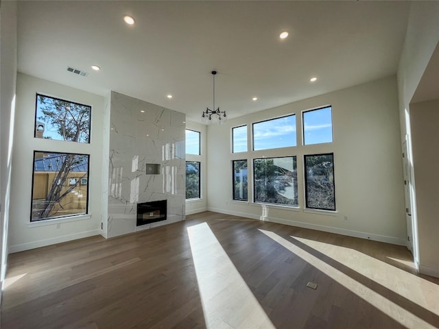 unfurnished living room with a high end fireplace, a notable chandelier, and dark hardwood / wood-style flooring