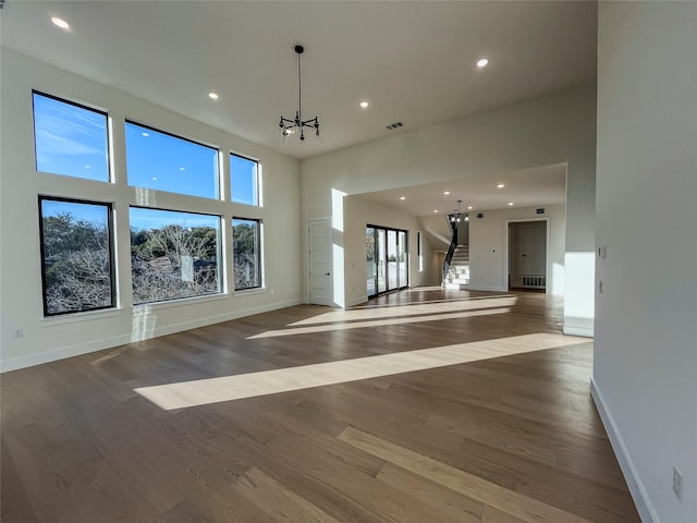 unfurnished living room featuring hardwood / wood-style flooring and a chandelier