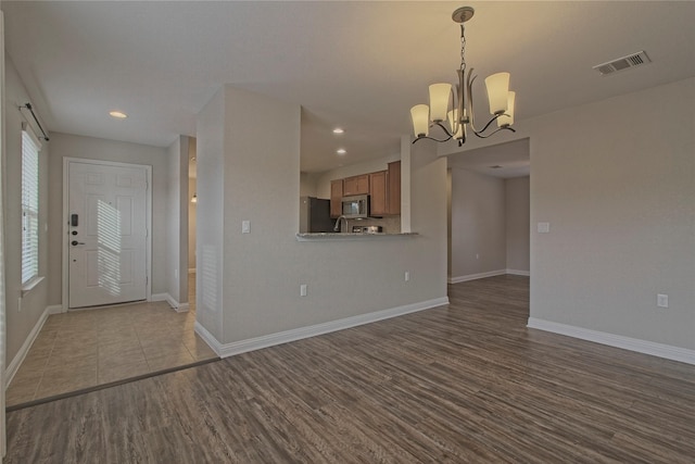 unfurnished living room with light hardwood / wood-style floors and a notable chandelier