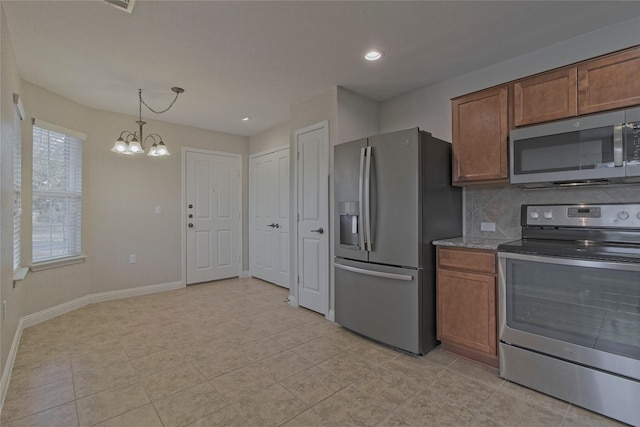 kitchen with decorative light fixtures, an inviting chandelier, light stone counters, tasteful backsplash, and appliances with stainless steel finishes