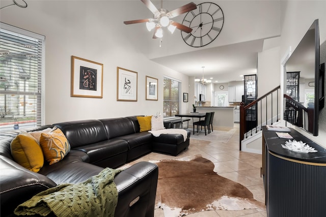 living room with light tile patterned flooring and ceiling fan with notable chandelier