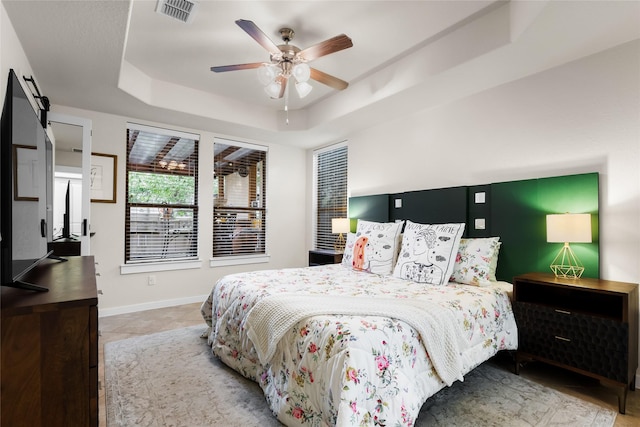 bedroom with ceiling fan, a barn door, and a tray ceiling