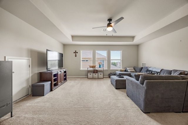 carpeted living room with ceiling fan and a raised ceiling