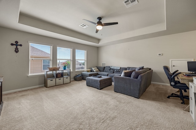 living room featuring ceiling fan, a tray ceiling, and light carpet