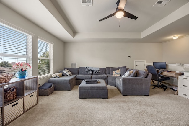 carpeted living room with ceiling fan and a raised ceiling