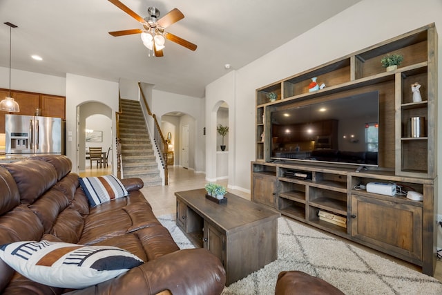 tiled living room with ceiling fan and built in shelves