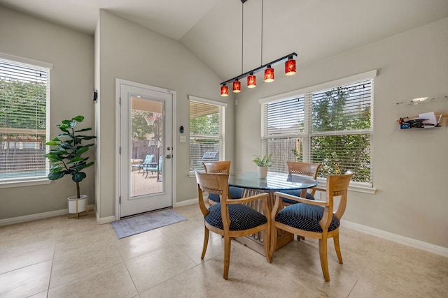 tiled dining space with a healthy amount of sunlight and lofted ceiling