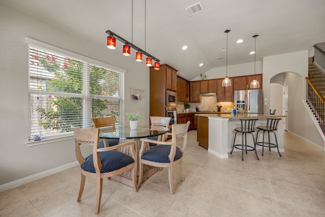 dining area with light tile patterned floors and vaulted ceiling