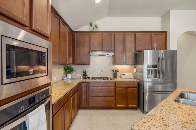 kitchen featuring appliances with stainless steel finishes, light stone counters, sink, lofted ceiling, and tasteful backsplash