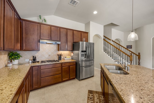 kitchen featuring light stone countertops, pendant lighting, stainless steel appliances, lofted ceiling, and sink