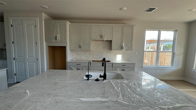 kitchen featuring white cabinetry, sink, and light stone counters