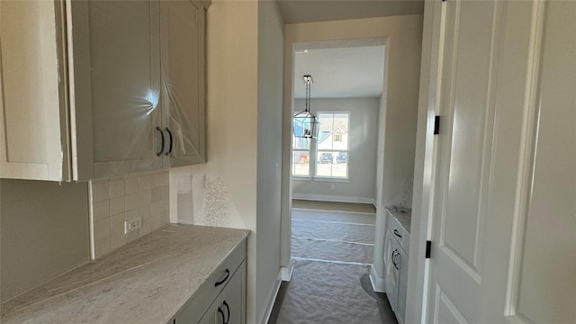 kitchen featuring light stone counters, hanging light fixtures, decorative backsplash, and white cabinets