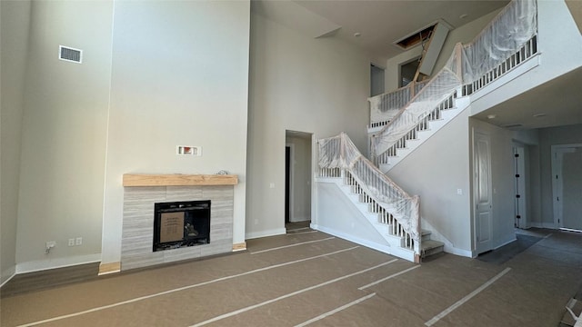 unfurnished living room featuring a high ceiling and a tile fireplace