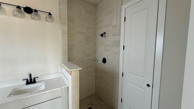 bathroom featuring tiled shower and vanity