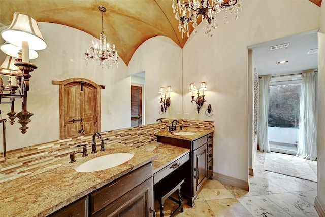 bathroom featuring an inviting chandelier, lofted ceiling, vanity, and backsplash