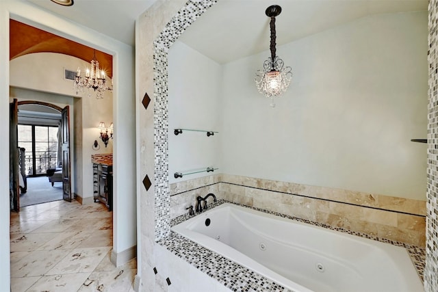 bathroom featuring tiled bath, a chandelier, and vaulted ceiling