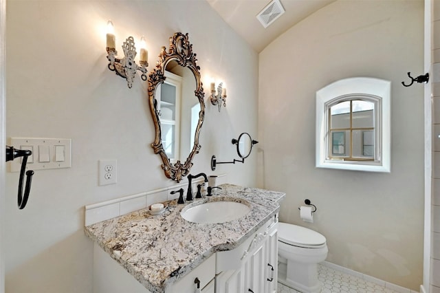 bathroom featuring tile patterned floors, vanity, toilet, and vaulted ceiling