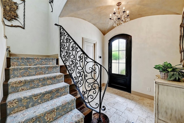 2433 Westlake Dr, Austin, TX 78746 - entryway featuring baseboards, arched walkways, vaulted ceiling, stone tile floors, and a chandelier
