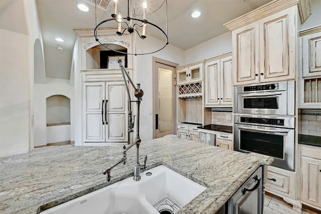 kitchen with decorative backsplash, light stone countertops, double oven, and hanging light fixtures