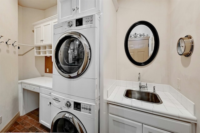 laundry area featuring sink, cabinets, and stacked washing maching and dryer