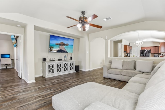 living room featuring ceiling fan with notable chandelier, dark hardwood / wood-style flooring, and vaulted ceiling