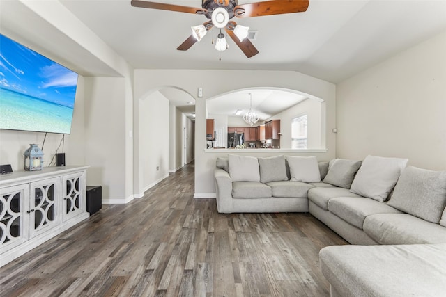 living room with ceiling fan with notable chandelier, dark hardwood / wood-style flooring, and vaulted ceiling