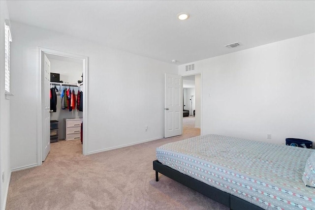 bedroom with light colored carpet, a spacious closet, and a closet