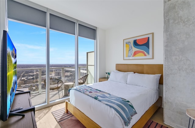 bedroom with access to outside, wood-type flooring, and expansive windows