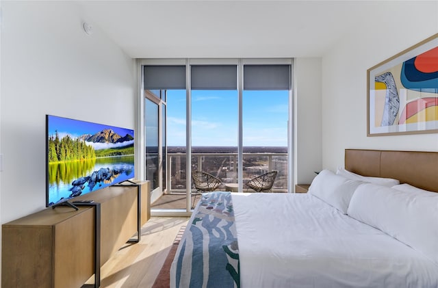 bedroom featuring expansive windows and light hardwood / wood-style floors