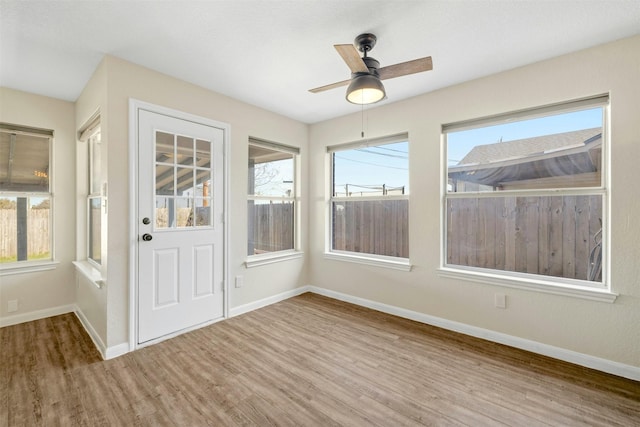 unfurnished sunroom with ceiling fan