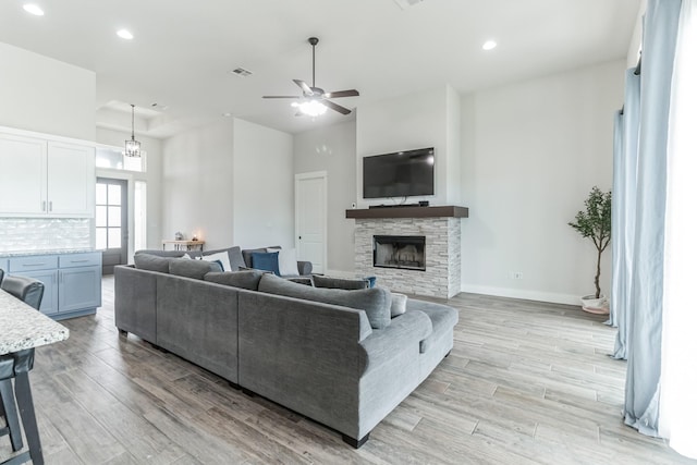 living room featuring ceiling fan and a stone fireplace