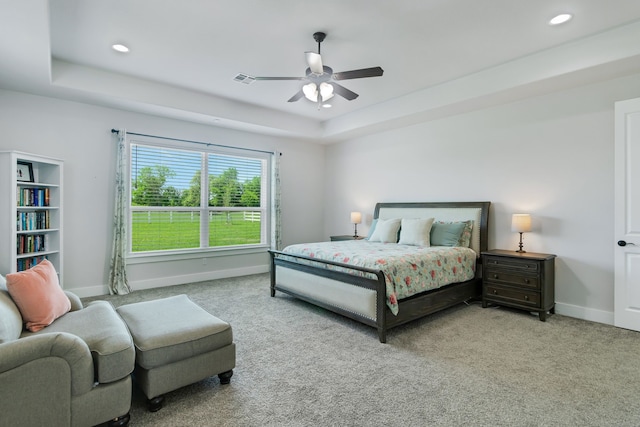 bedroom with a raised ceiling, light carpet, and ceiling fan