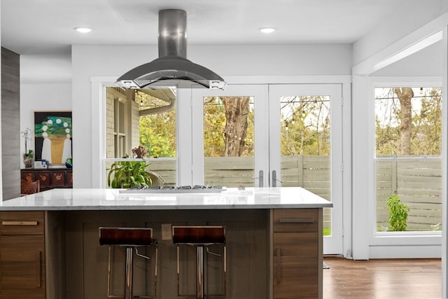 interior space featuring light stone counters, white gas stovetop, island exhaust hood, and light hardwood / wood-style floors