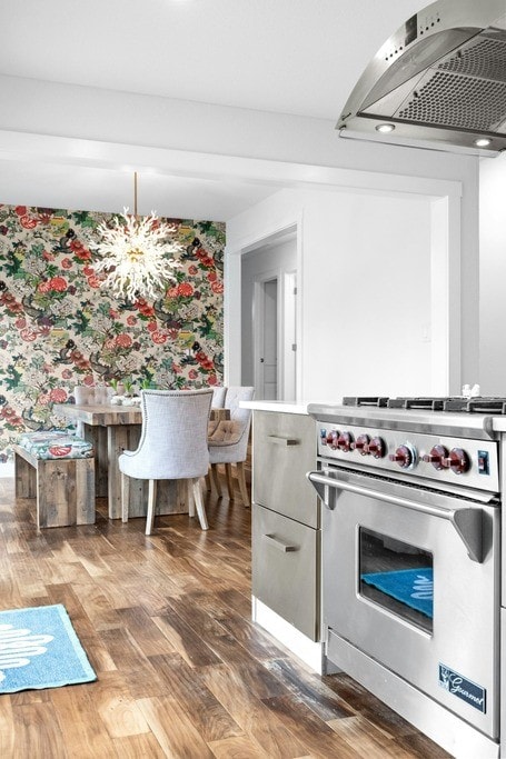 kitchen with ventilation hood, dark hardwood / wood-style floors, a notable chandelier, and high end stainless steel range