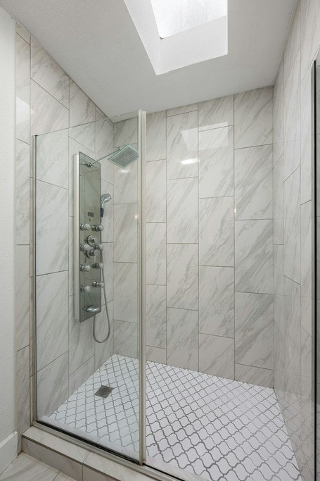 bathroom with a shower with door and a skylight