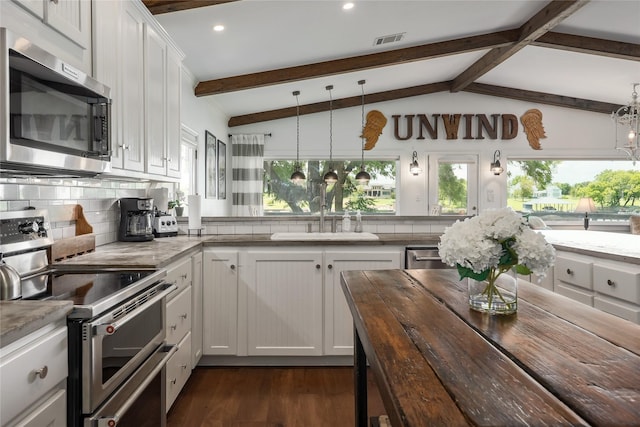 kitchen featuring stainless steel appliances, white cabinetry, vaulted ceiling with beams, and pendant lighting