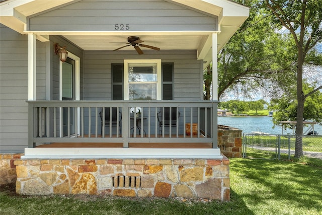 doorway to property featuring ceiling fan, a porch, a water view, and a lawn