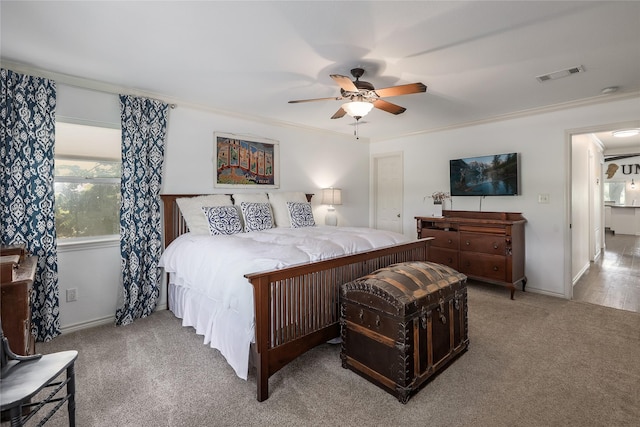 bedroom featuring ornamental molding, light colored carpet, and ceiling fan