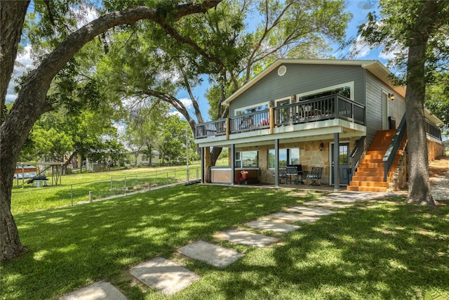 rear view of house with a yard, a wooden deck, and a patio